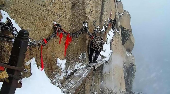 Workers Sweep Snow From A Cliff Path