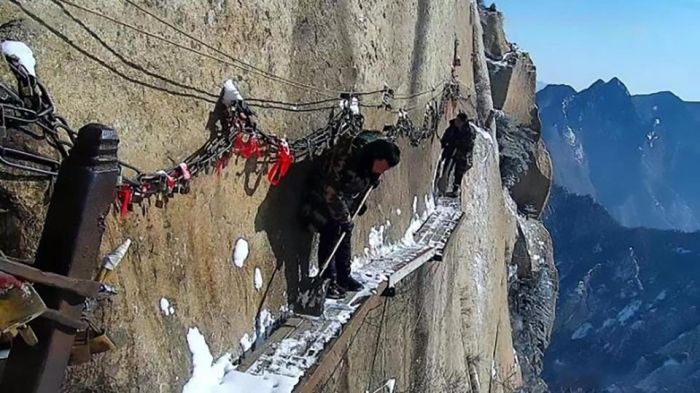 Workers Sweep Snow From A Cliff Path